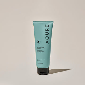 A tube of ACURE Ultra Hydrating Shampoo against a neutral background.